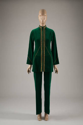 Green pantsuit of tunic jacket with stand collar and gold metallic ribbon and braid edging and …