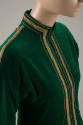 Detail view of green tunic jacket showing gold ribbon and braid trim across shoulders, around c…