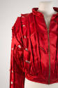 Detail view of red bomber jacket showing corded seams and edging and exposed white burlap in sl…
