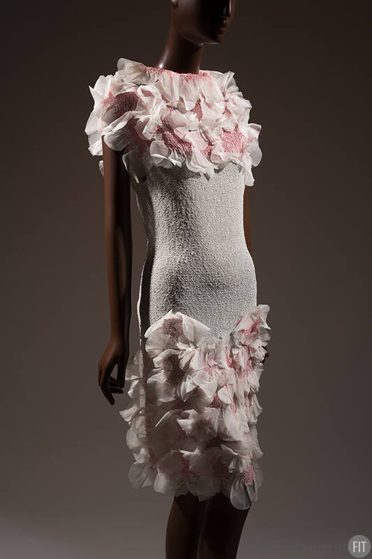 White dress with white and pink rosettes at neckline and bottom of skirt 