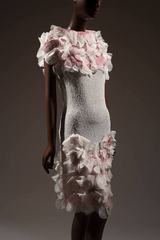 White dress with white and pink rosettes at neckline and bottom of skirt 