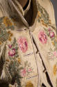 Embroidered pink, yellow, and green floral motif on light beige jacket with collar