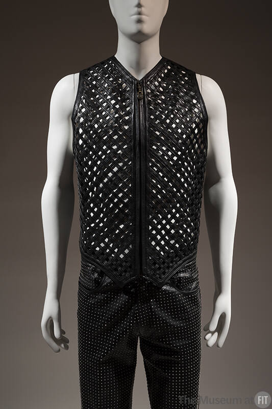 Black zippered vest with lattice front strips, belt buckle embossed with classical motifs style…