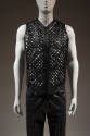 Black zippered vest with lattice front strips, belt buckle embossed with classical motifs style…