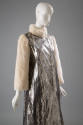 Detail of metallic silver snakeskin coat with white fur collar and long sleeves