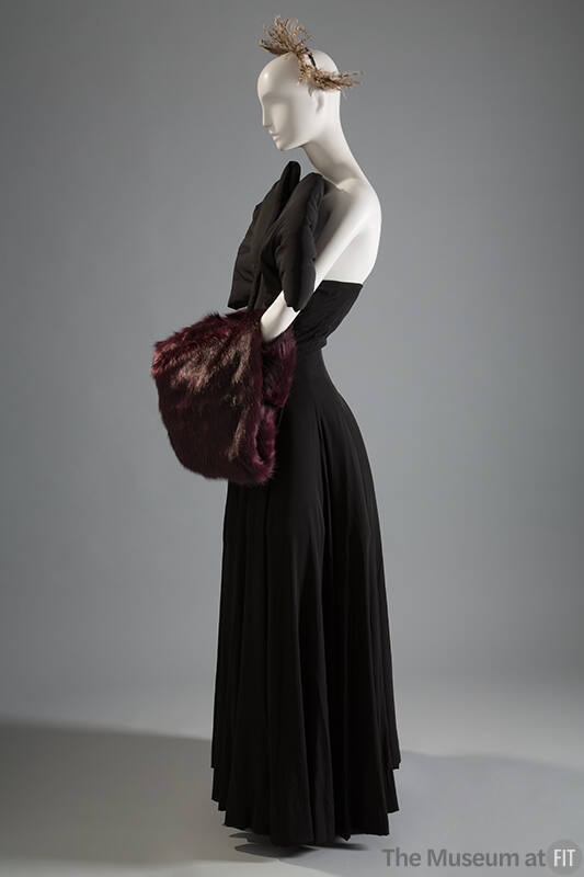 Black strapless floor length dress with padded piece at bodice and large red faux fur muff