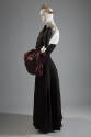 Black strapless floor length dress with padded piece at bodice and large red faux fur muff