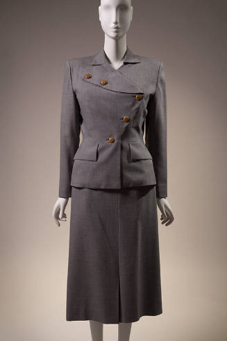 Grey suit with long sleeve jacket with asymmetric brown button front, flap pockets and matching…
