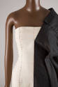 Detail of off-white one shoulder dress with black and red  topstitching and black draped sleeve