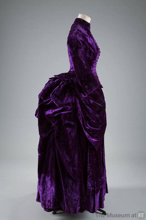 Purple dress with floor length bustle back skirt with draped and pleated puffs at hips