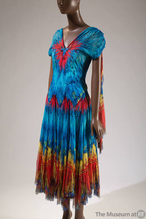 Blue, red, yellow and orange feather print evening dress with cap sleeves, scarf panel at back …