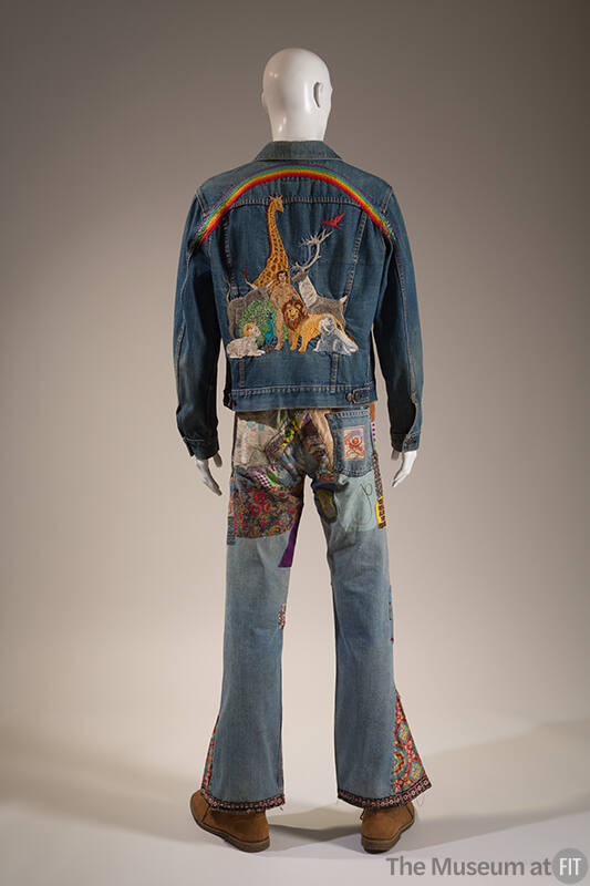Back view of man’s blue denim jacket embroidered with man, animals and rainbow and bell bottom …