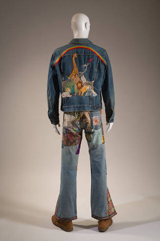 Back view of man’s blue denim jacket embroidered with man, animals and rainbow and bell bottom …