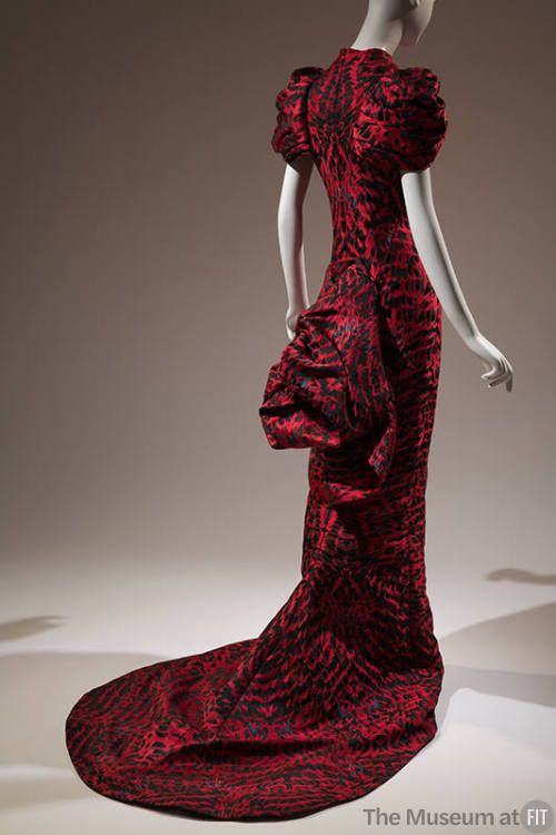 Back view of red and black feather printed fitted evening dress with short oversize puff sleeve…