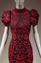 Detail view of red and black feather printed evening dress showing silk jacquard fabric and sea…