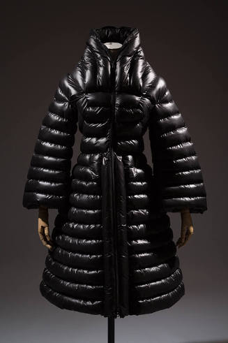 Black puffer coat with horizontal quilting, stand collar, bell sleeves, fitted waist and flared…