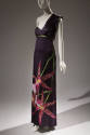 Dark grey one shoulder floor length dress with empire waist trimmed in green and oversize pink …
