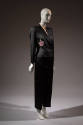 ¾ view of black evening pantsuit with double breasted jacket with pink rose embroidered at left…