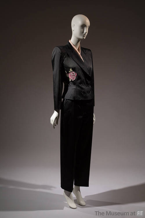 ¾ view of black evening pantsuit with double breasted jacket with pink rose embroidered at left…