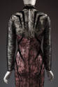 Back view of black lace evening dress showing black stylized appliques, keyhole neck closing an…