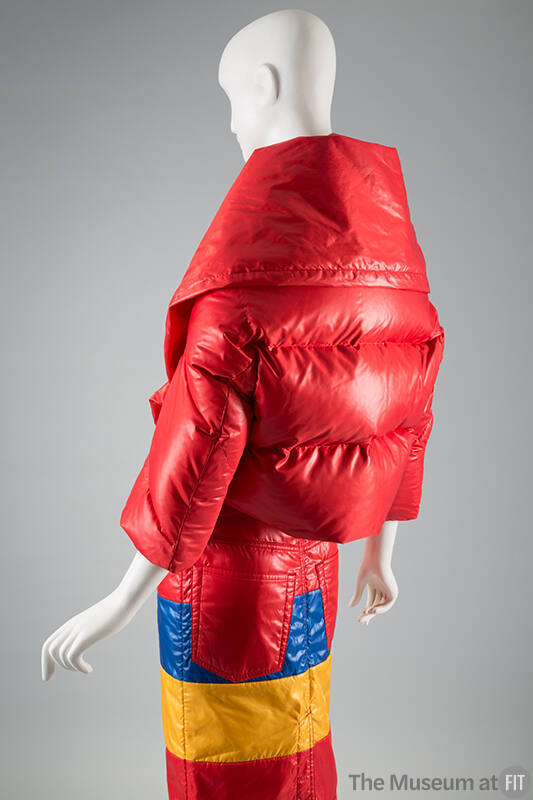 Back view of red puffer style jacket with horizontal quilting and oversize collar and fitted sk…