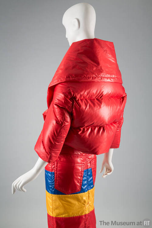 Back view of red puffer style jacket with horizontal quilting and oversize collar and fitted sk…