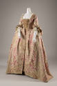 ¾ view of pink robe a la francaise gown with stylized ivory and green floral pattern, lace slee…
