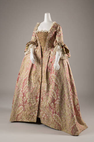¾ view of pink robe a la francaise gown with stylized ivory and green floral pattern, lace slee…