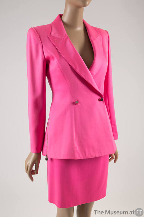 Bright pink suit of peak lapel jacket with side zipper and two button closure in the shape of s…