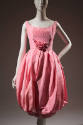 Pink sleeveless dress with above-the-knee bubble skirt and large rose attached to center waist