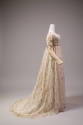 Side view of white muslin long sleeve dress with allover embroidered vines and floral springs, …