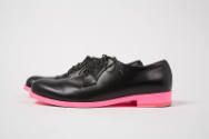 Pair of man’s black lace up shoes with neon pink soles