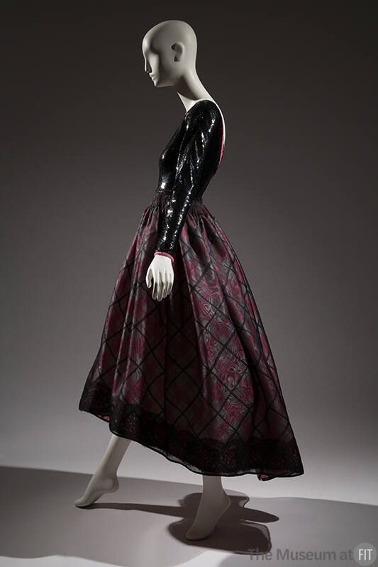 Side view of evening dress with black sequined long sleeve bodice and pink, white and black pla…
