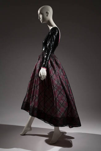 Side view of evening dress with black sequined long sleeve bodice and pink, white and black pla…