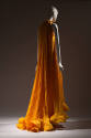 Back view of pleated dark yellow floor length halter dress with ruffled high neckline and ruffl…