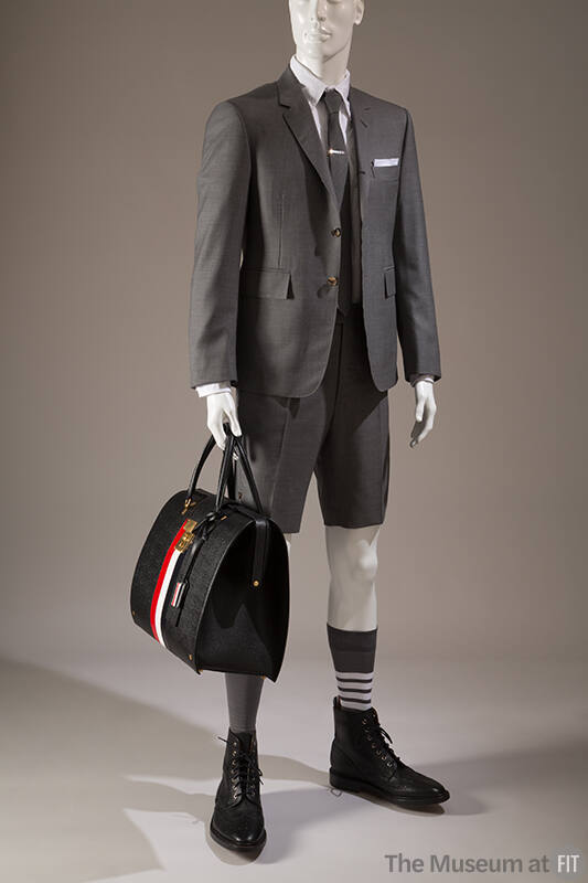 Grey suit with long sleeve blazer, matching Bermuda shorts, black ankle boots and large black l…