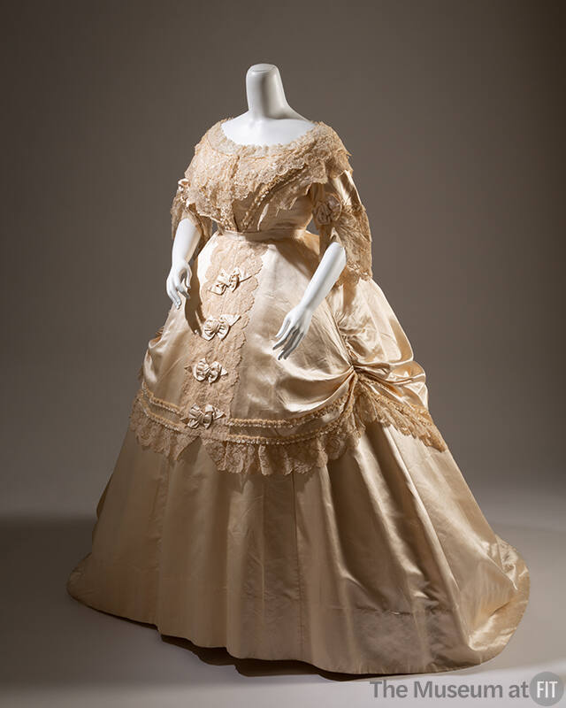 Cream silk satin dress with lace overlay on bodice, ¾ length sleeves with ruffles and wide floo…