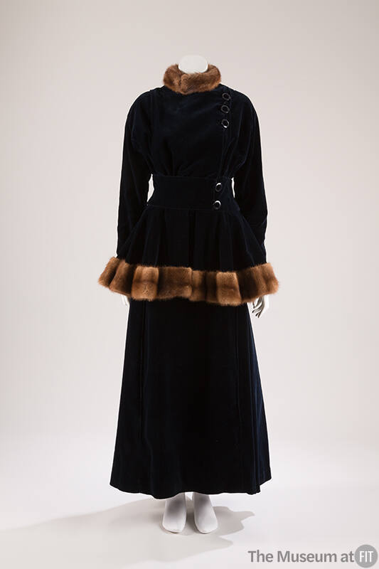 Dark blue velvet jacket with side buttons and brown fur trim on stand collar and peplum hem wit…
