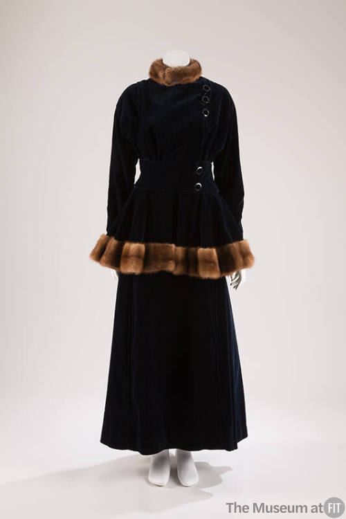 Dark blue velvet jacket with side buttons and brown fur trim on stand collar and peplum hem wit…