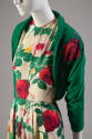 Detail view of ivory dress showing red, yellow and pink rose print on fabric and red rose appli…
