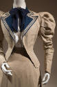 Detail view of linen summer suit showing jacket with puffed shoulders, navy blue lapels with wh…