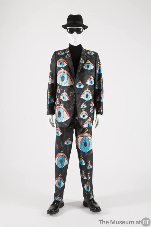 Man’s dark blue suit with allover painted orange, blue, gold, white and black eyes of various s…