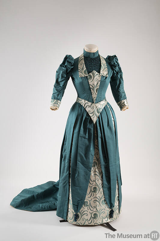 Blue green two-piece floor length dress with puffed sleeves, white and blue green brocade trim …