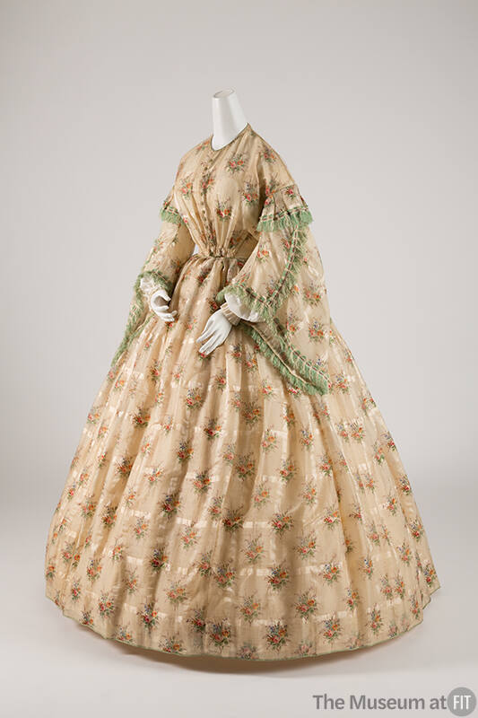 Beige floor length dress in multicolor floral print with large bell sleeves trimmed with green …