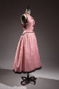 3/4 view of sleeveless pink ad white striped vest and pink and white striped full skirt with bl…