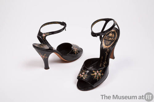 Pair of black high heel ankle strap sandals with painted flowers throughout and gold Delman log…