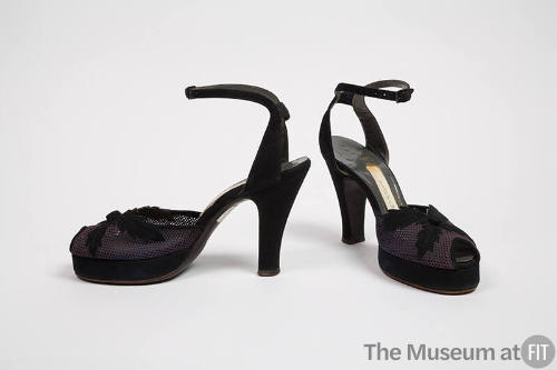 Pair of navy open toe ankle strap high heel sandals with bar across ankle and x-shaped leaf app…