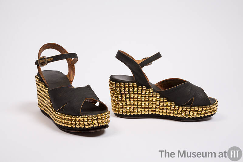 Pair of black platform sandals with crossing straps at vamp, ankle strpas gold-studded wedge he…