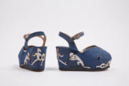 Pair of blue wedge sandals with silver metallic piping, appliqué warrior figures on the platfor…