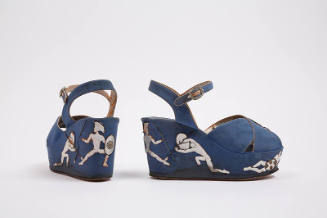 Pair of blue wedge sandals with silver metallic piping, appliqué warrior figures on the platfor…